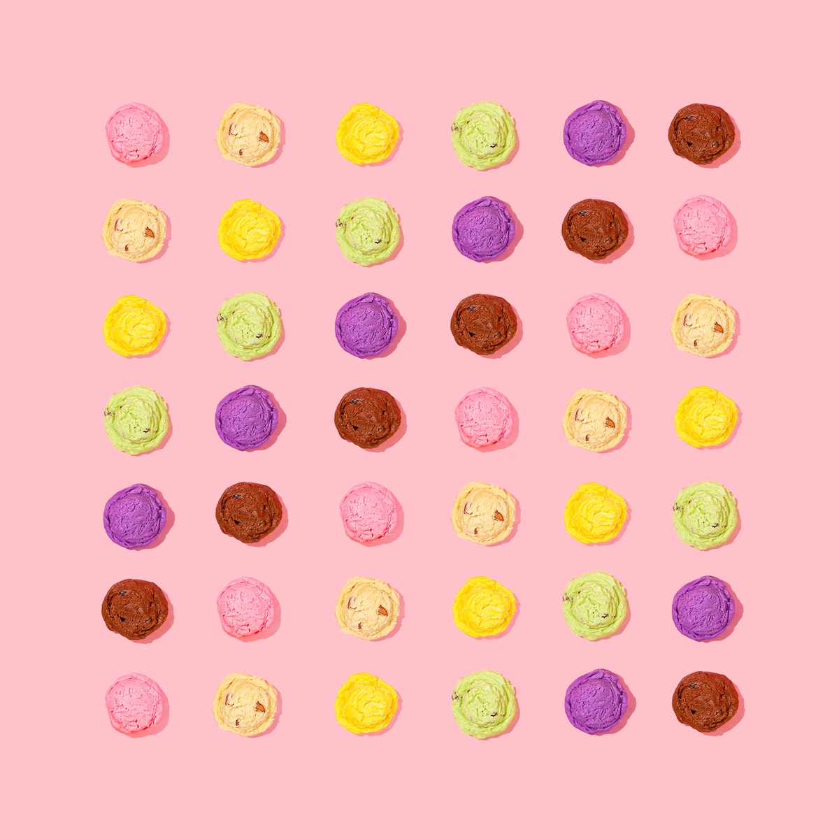 Bolas de helado de varios colores sobre fondo rosa